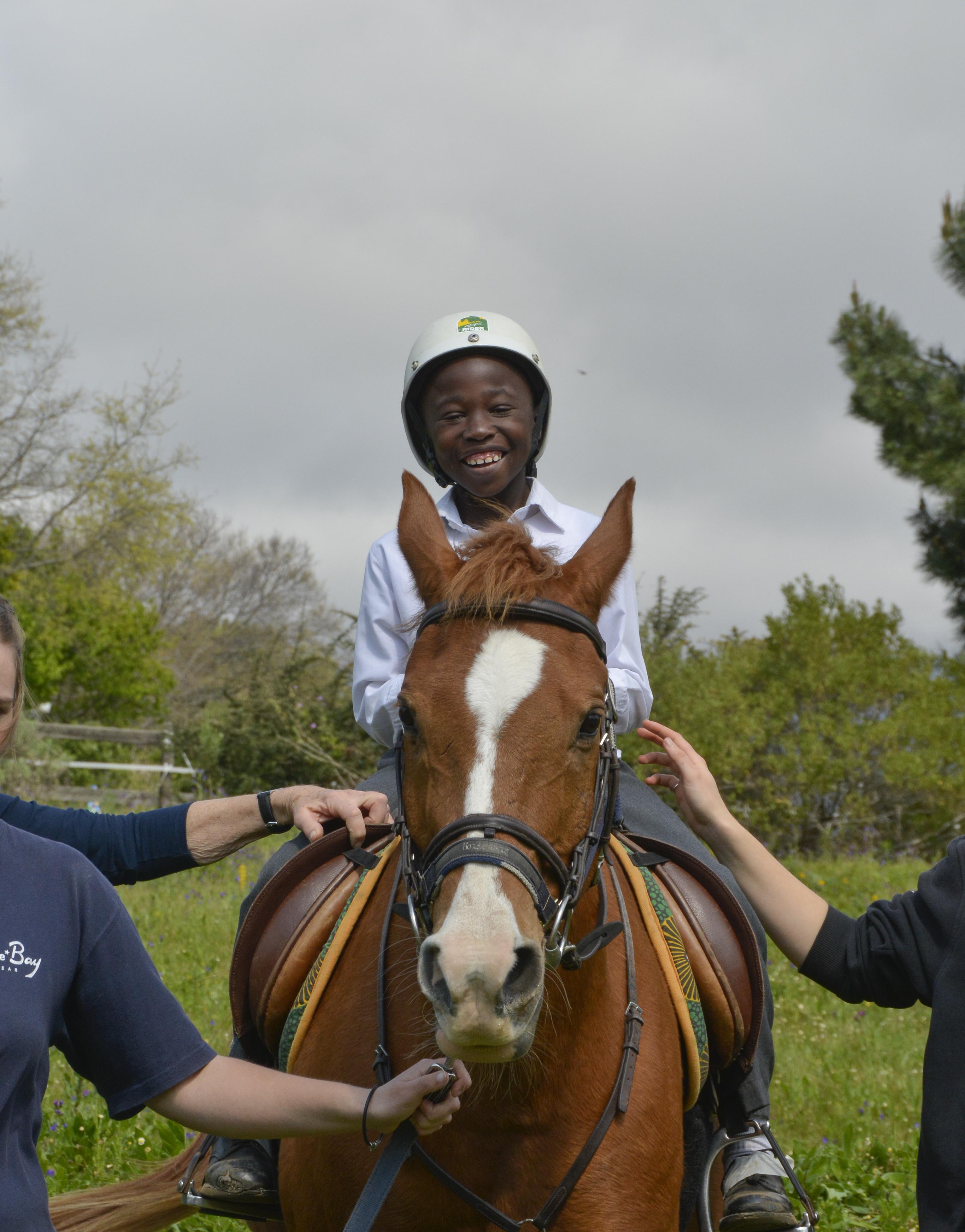 Young boy rides a horse during an Equine Therapy session run by Projects Abroad interns in South Africa. Projects Abroad Equine Therapy interns supervise a young boy as he rides a horse during a therapy session in Cape Town, South Africa.